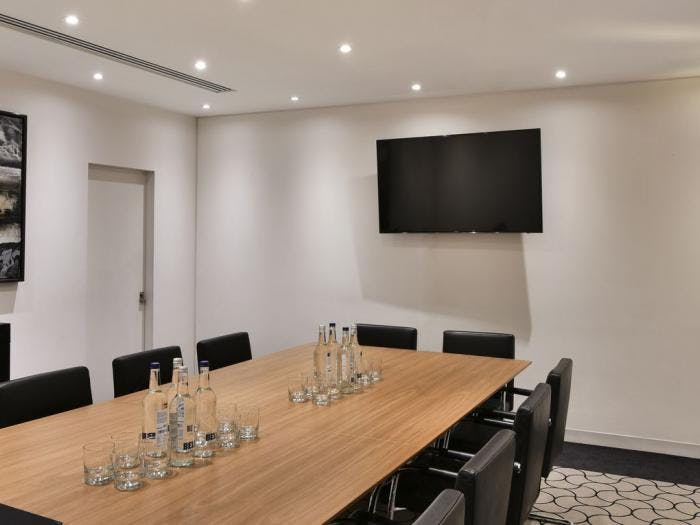 Modern purple meeting room with wooden table, ideal for professional gatherings and presentations.