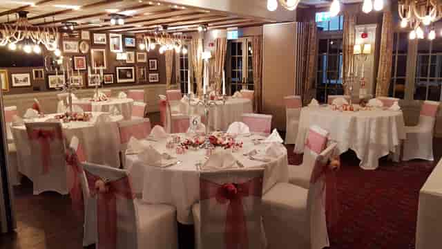 Elegant wedding venue with round tables, soft pink accents, and warm lighting.