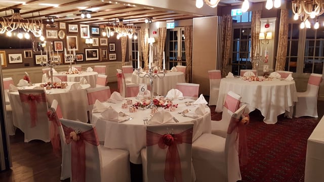 Elegant wedding venue with round tables, soft pink accents, and warm lighting.