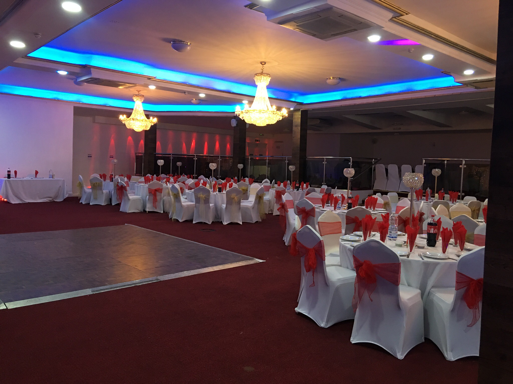 Banquet setup at Praba Banqueting Suite with red sashes, dance floor, and blue ambient lighting.