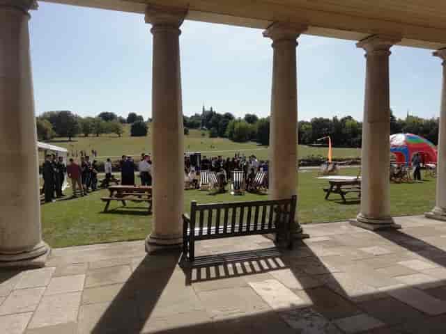 Vibrant outdoor event at South Lawns, The Queen's House with lush greenery and elegant columns.