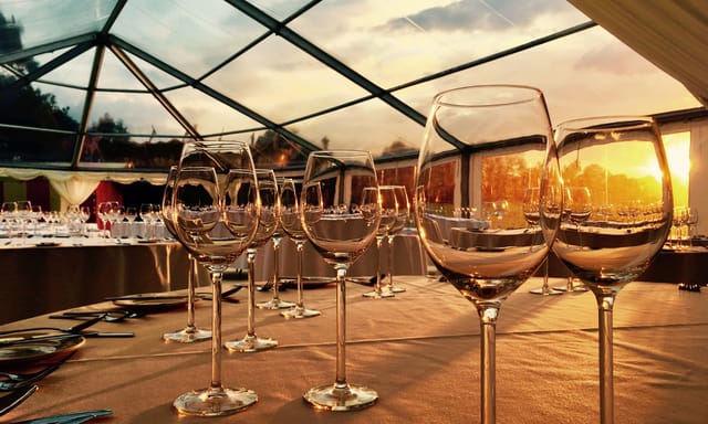 Elegant dining setup under glass canopy at South Lawns, perfect for upscale events.