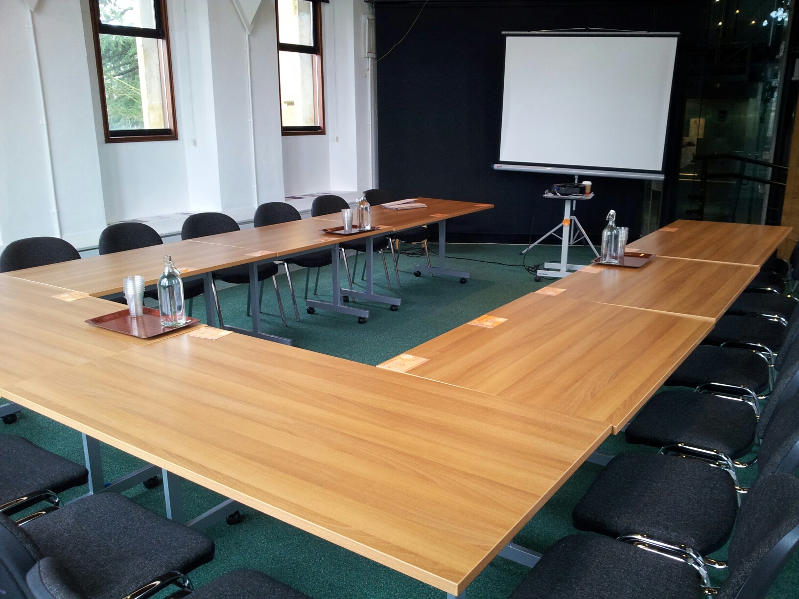 Apex meeting room with U-shaped table setup for collaborative session and presentations.