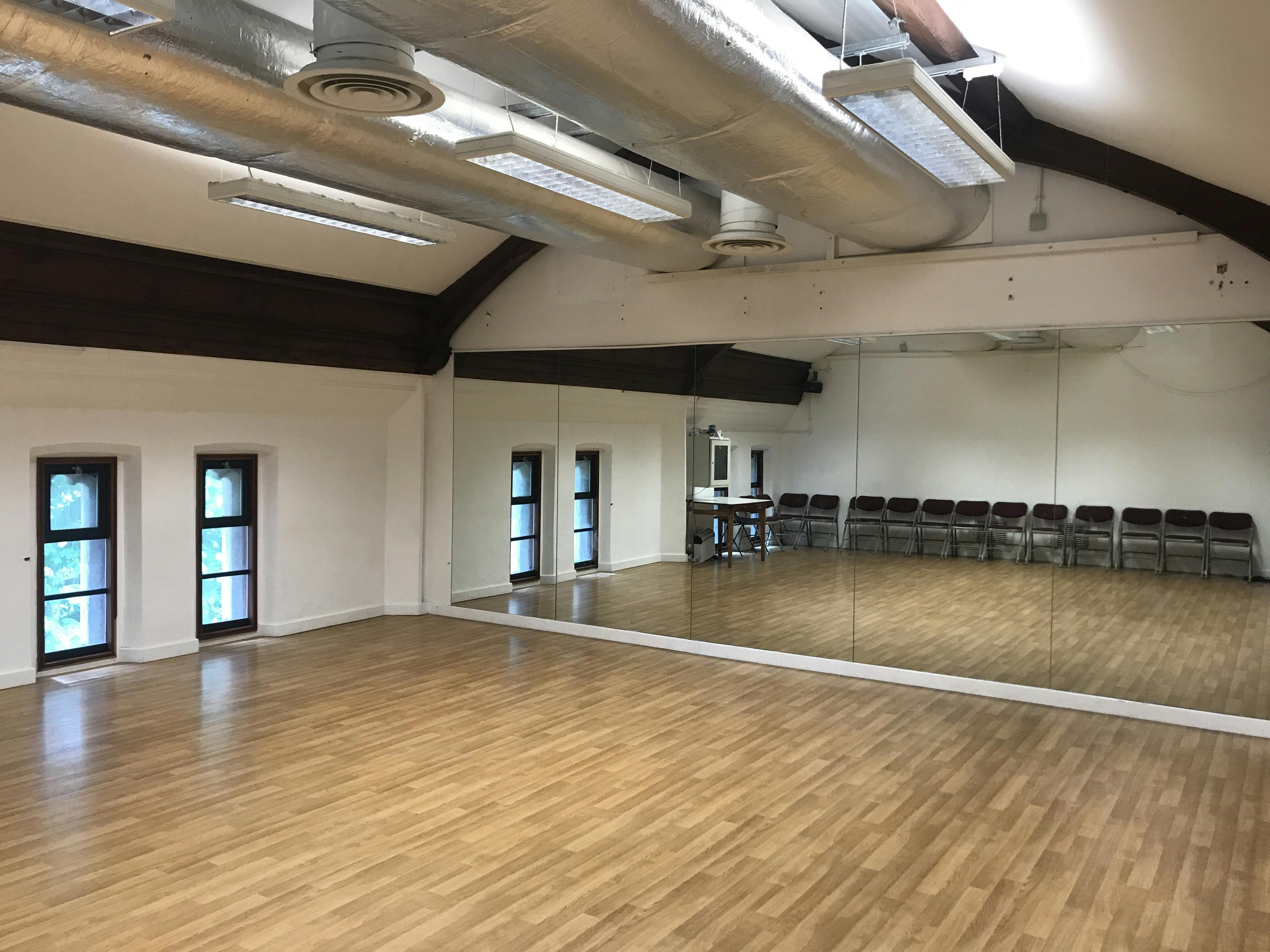 Dance studio with wooden floor and mirrors, perfect for workshops and fitness classes.