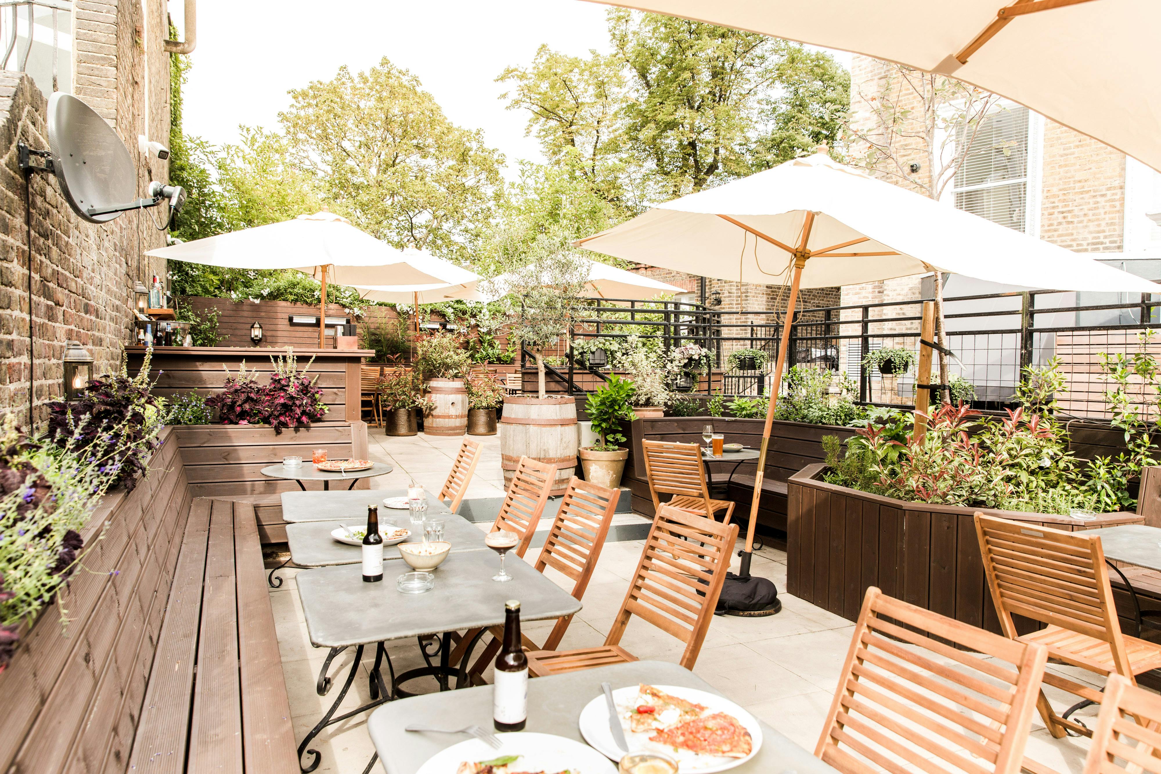 Charming outdoor garden venue with wooden tables for casual meetings and events.