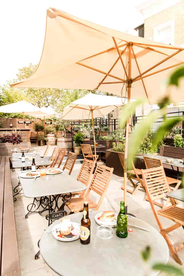 Charming outdoor garden venue with wooden tables for casual meetings and events.