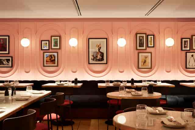Stylish restaurant interior with pink walls, ideal for intimate gatherings or networking events.