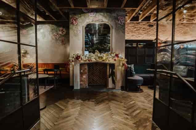 Elegant event space in The Gun London with floral decor and cozy fireplace.