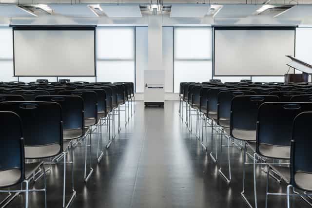 Main hall at London Academy of Excellence Tottenham, modern event space with black chairs.