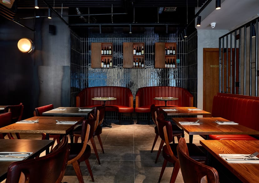 Modern restaurant interior with wooden tables and red banquettes for events at Gunpowder Tower.