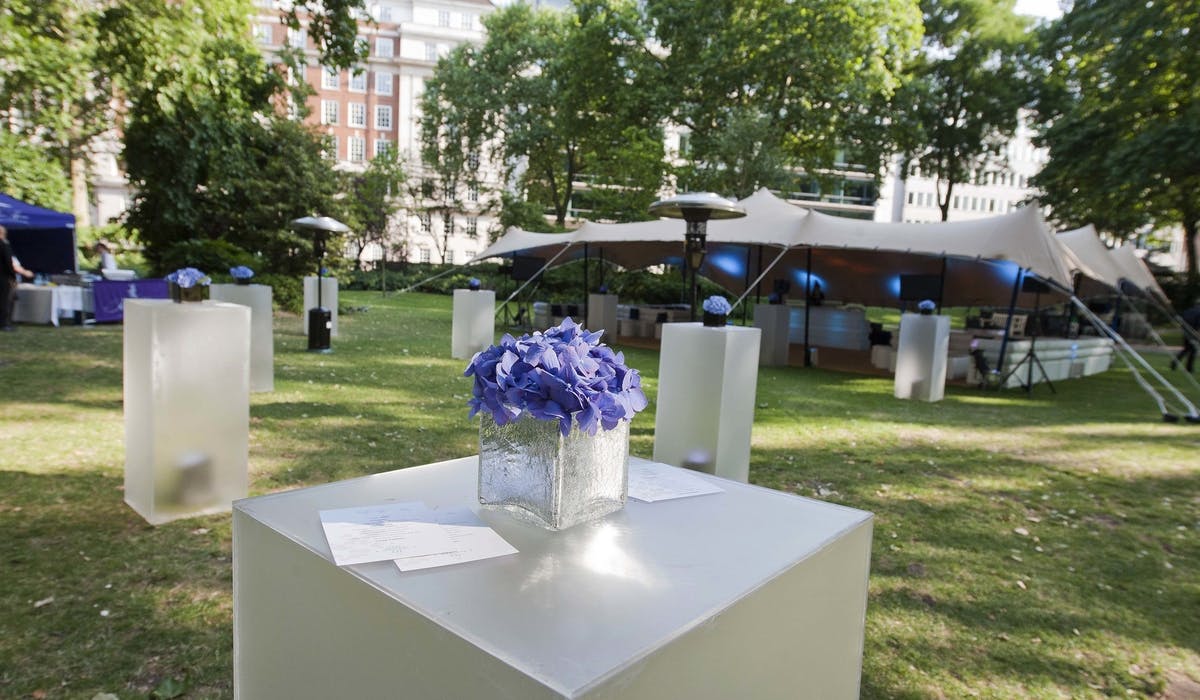 "Elegant outdoor event space at Portman Square Garden with floral centerpiece and tent."