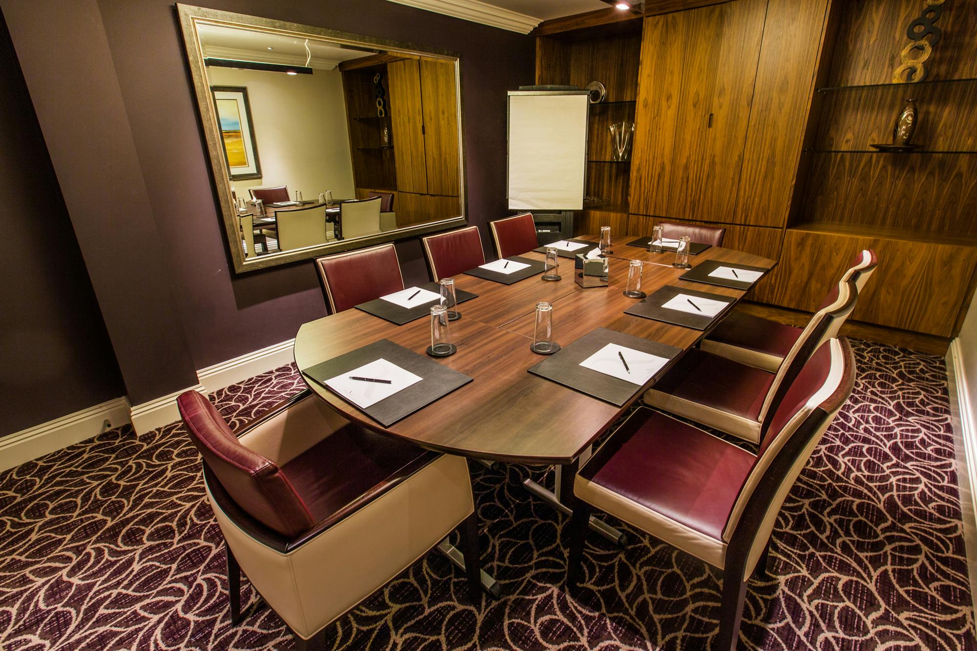 Intimate meeting room at Stanwick, featuring an oval table and warm wood accents.