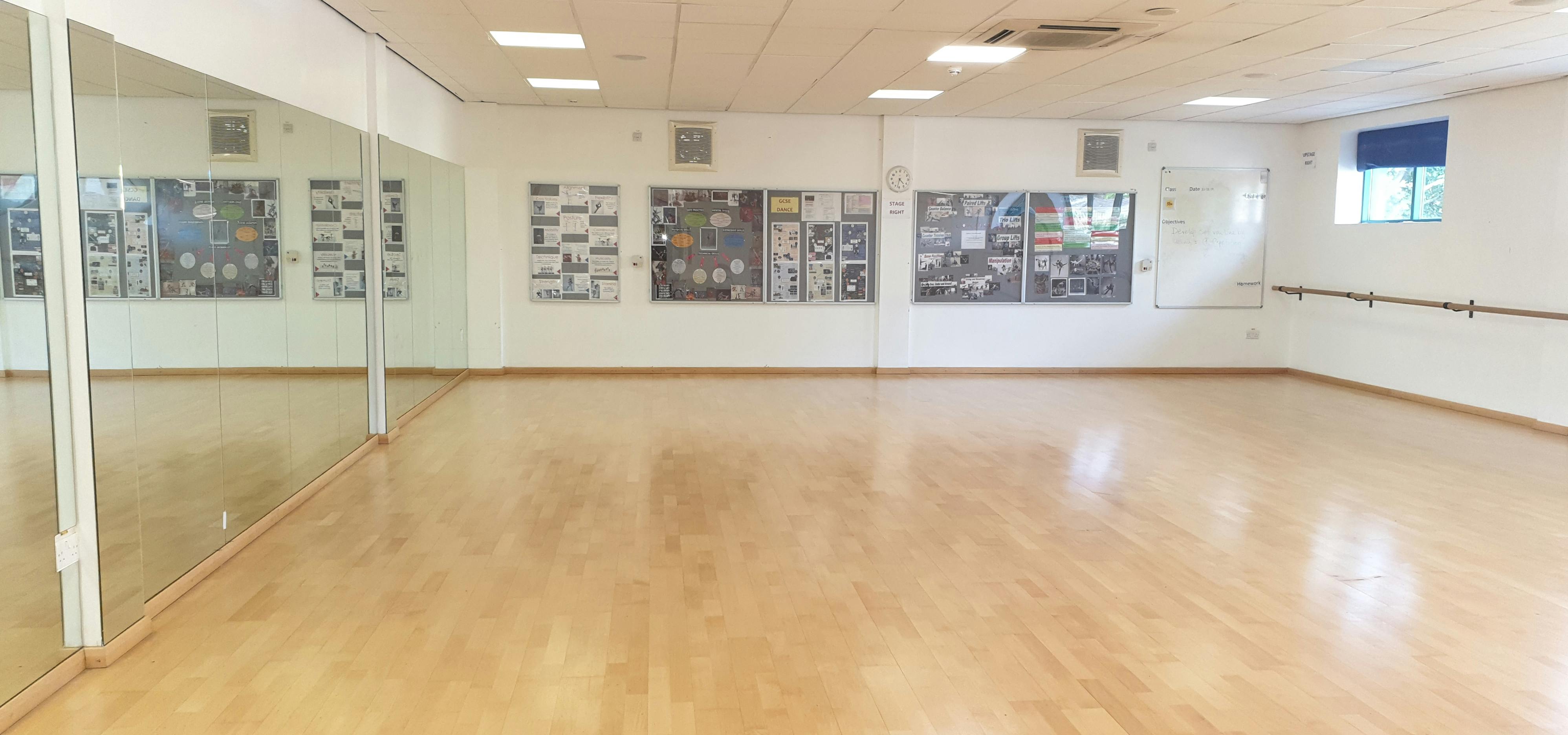 Dance studio with polished wooden floors, ideal for workshops and gatherings.