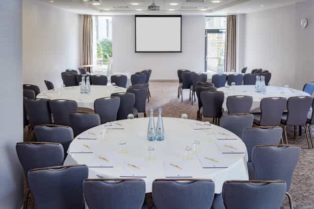 Claremont Suite meeting space with round tables, ideal for professional events and networking.