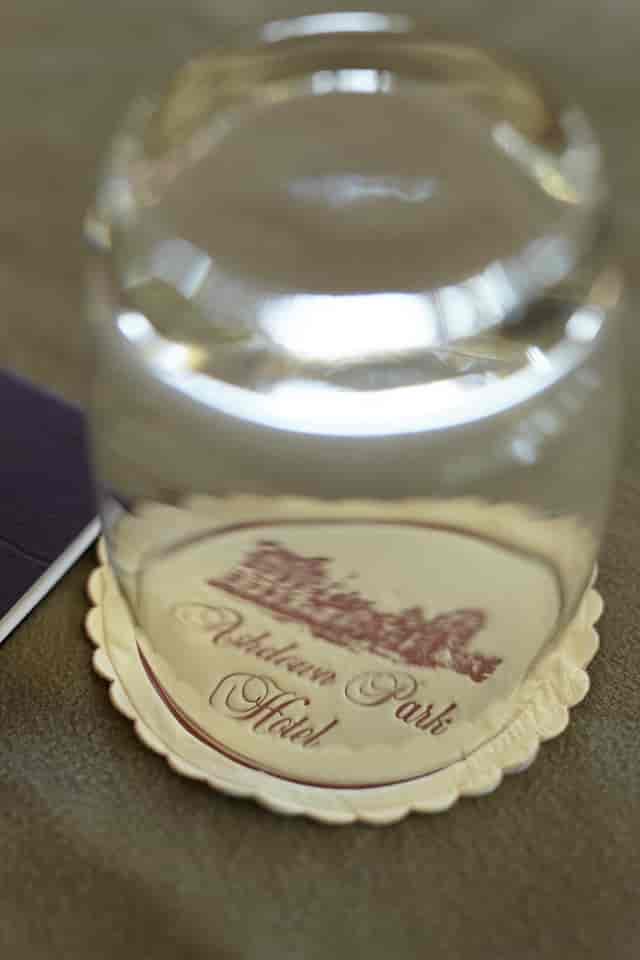 Geoffrey Webb at Ashdown Park: elegant water glass on branded coaster for corporate events.