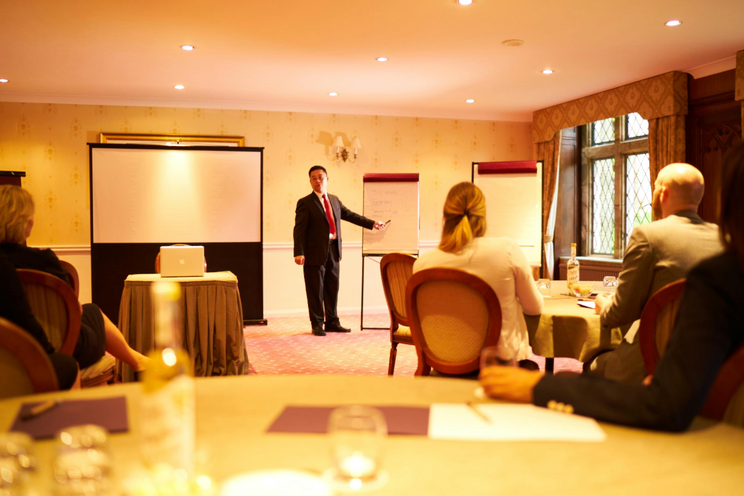 Lady Brassey speaking at a corporate meeting in Ashdown Park Hotel, featuring round tables.