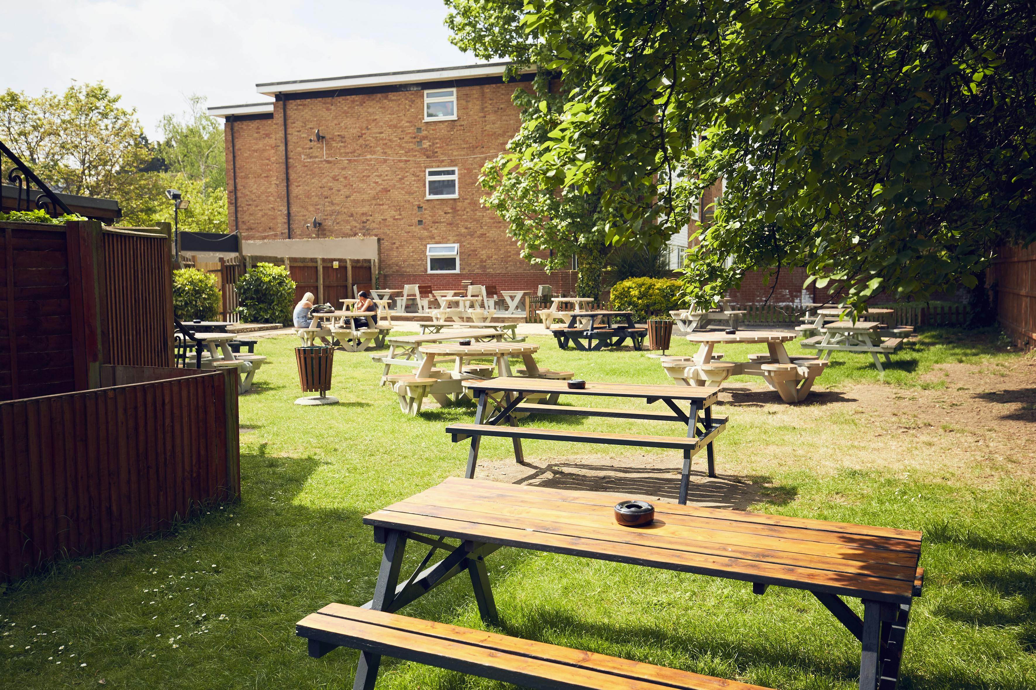 Outdoor event space with picnic tables in a garden for casual gatherings and team-building.