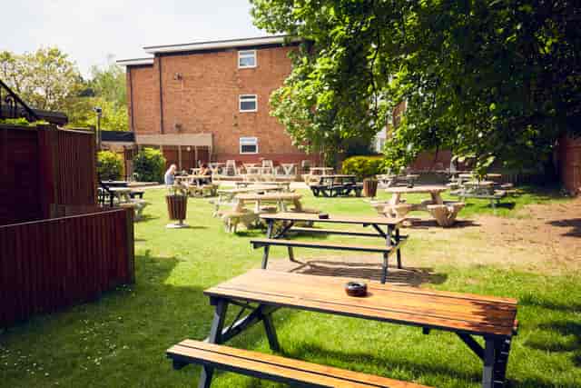 Outdoor event space with picnic tables in a garden for casual gatherings and team-building.
