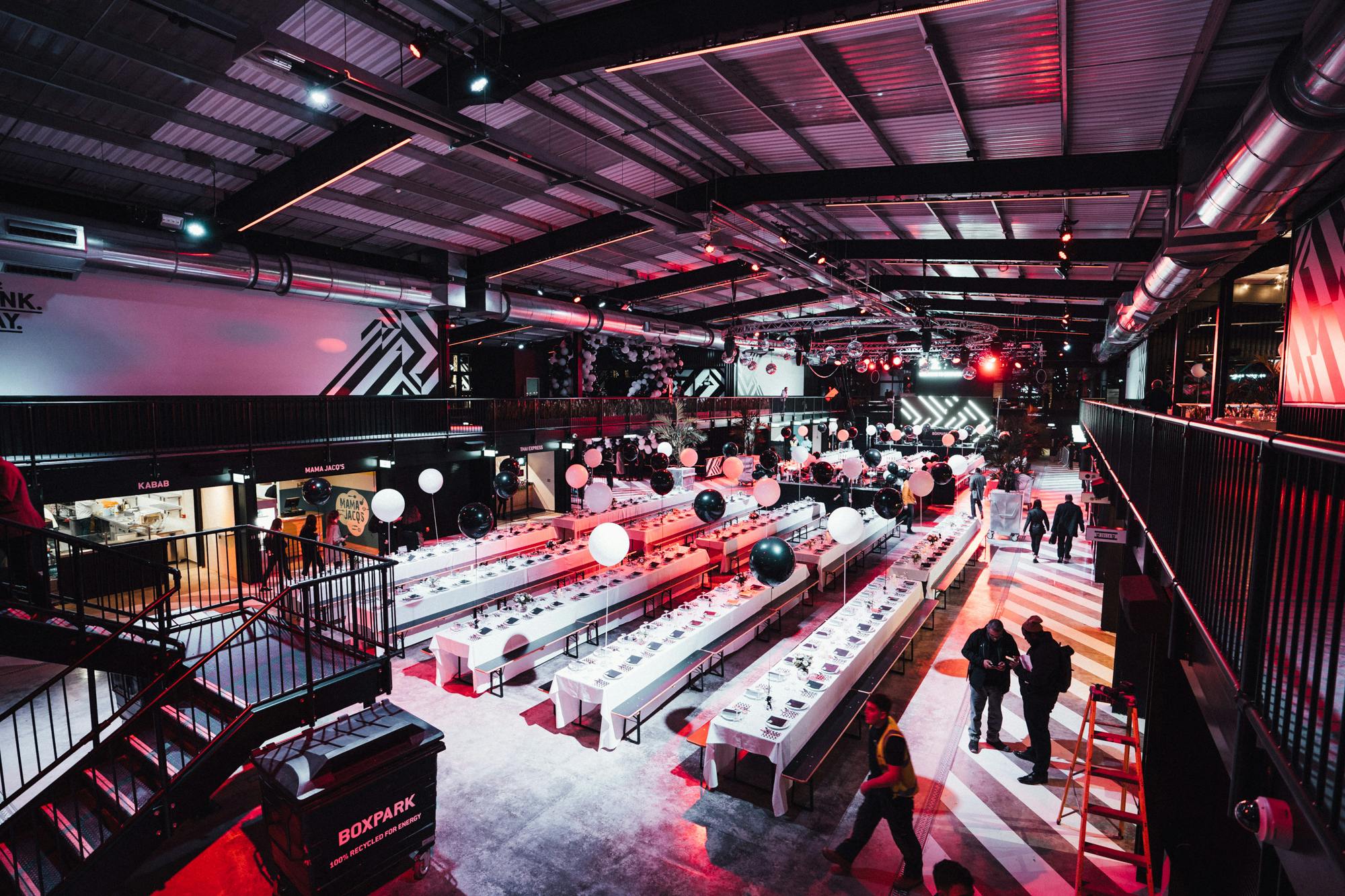 Spacious industrial event venue with banquet tables at Boxpark Wembley for gatherings.