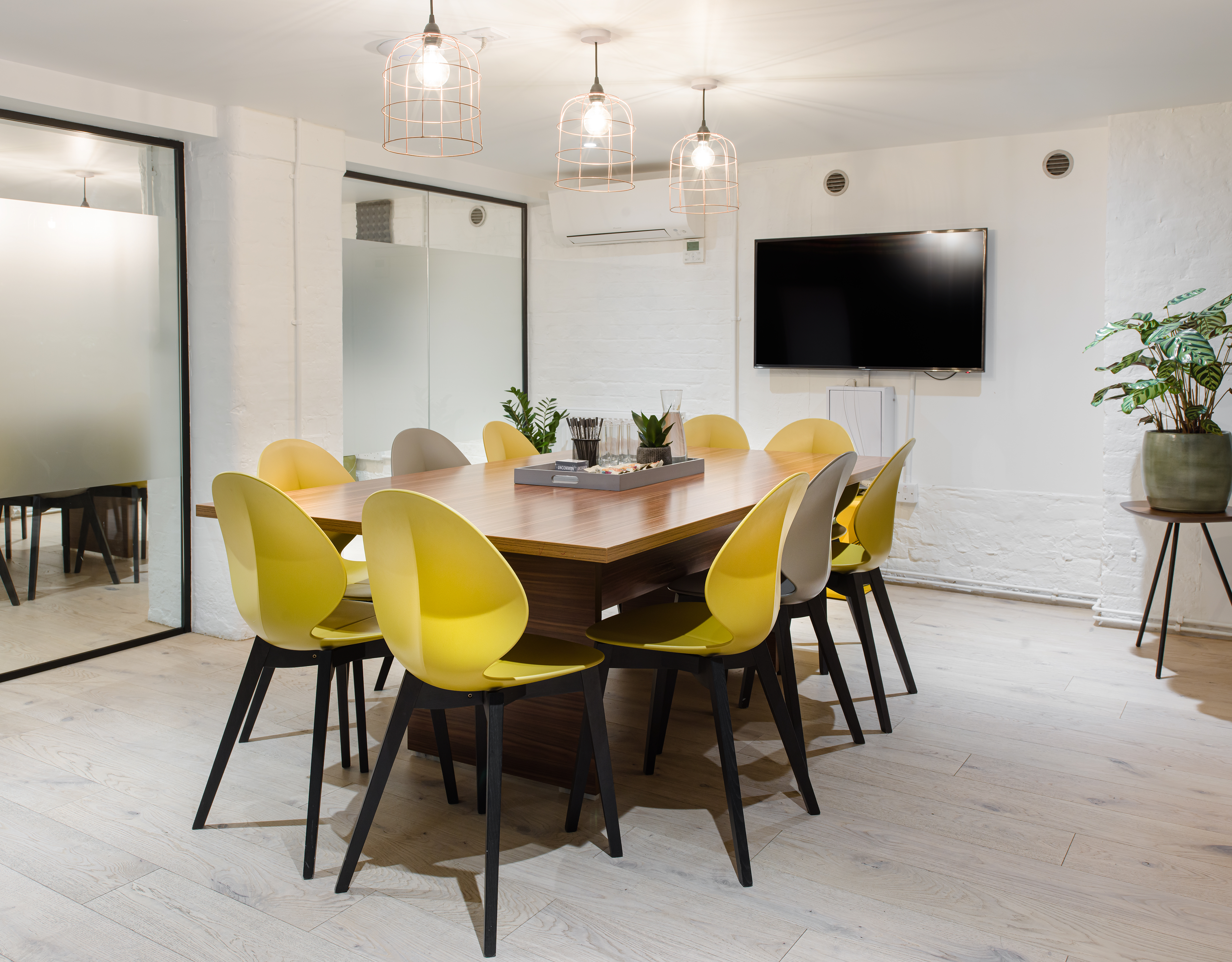 Modern meeting room with wooden table and vibrant yellow chairs for workshops.