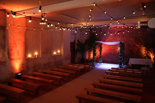 Intimate event space with floral archway and rustic brick walls at Loft Studios.
