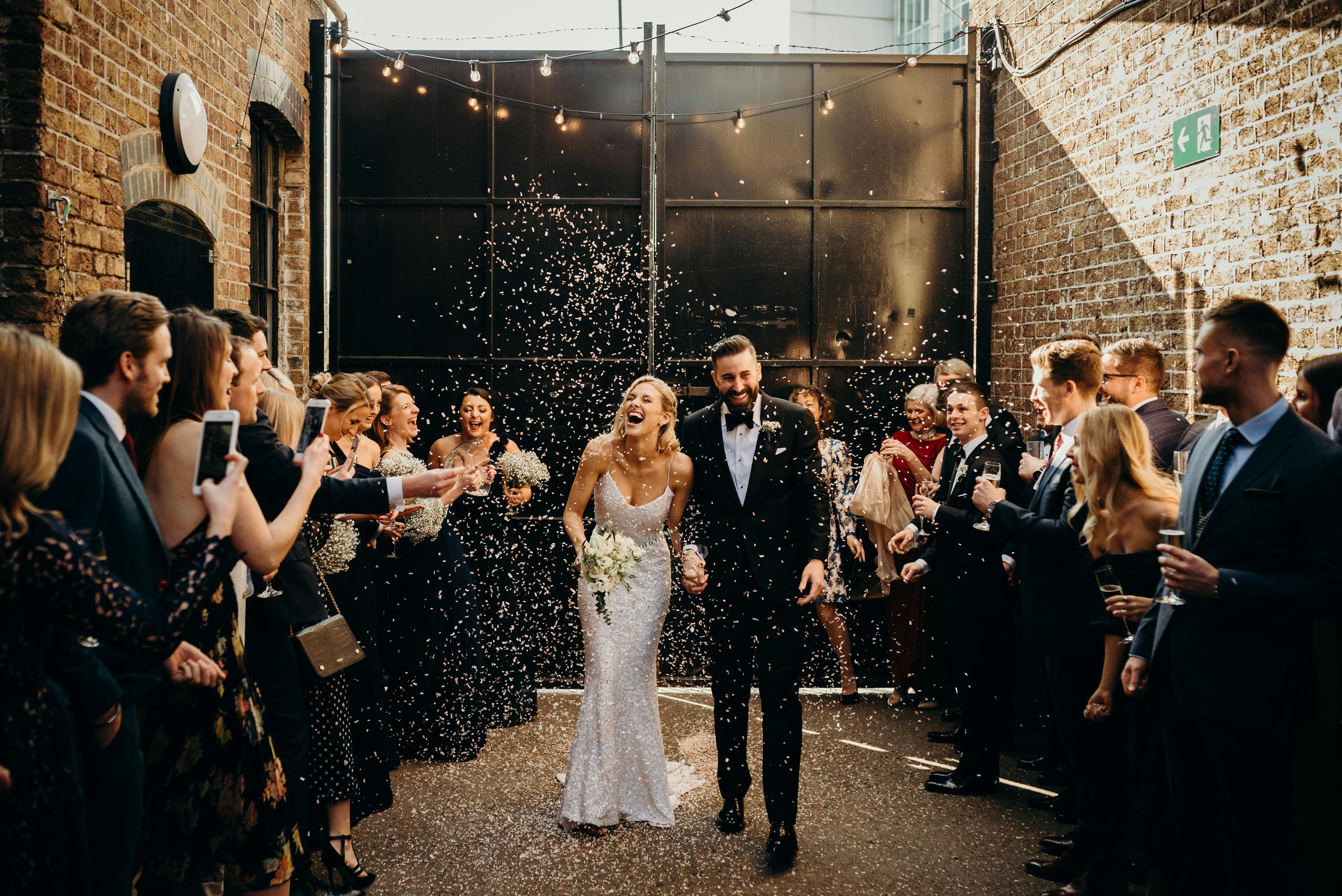 Joyful couple exiting wedding venue with confetti in Daylight Courtyard, Loft Studios.