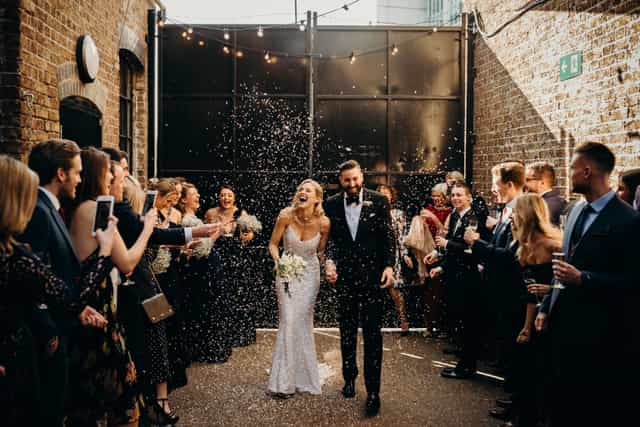 Joyful couple exiting wedding venue with confetti in Daylight Courtyard, Loft Studios.