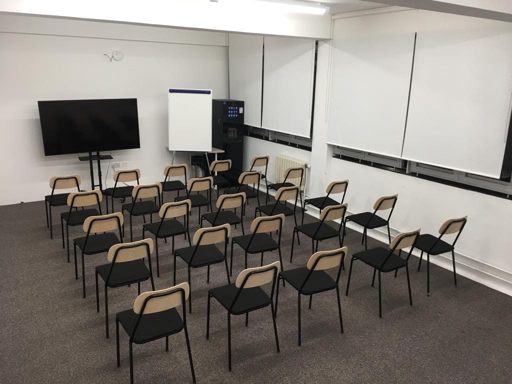 Minimalist seminar room with chairs and large screen for workshops in Whitechapel.