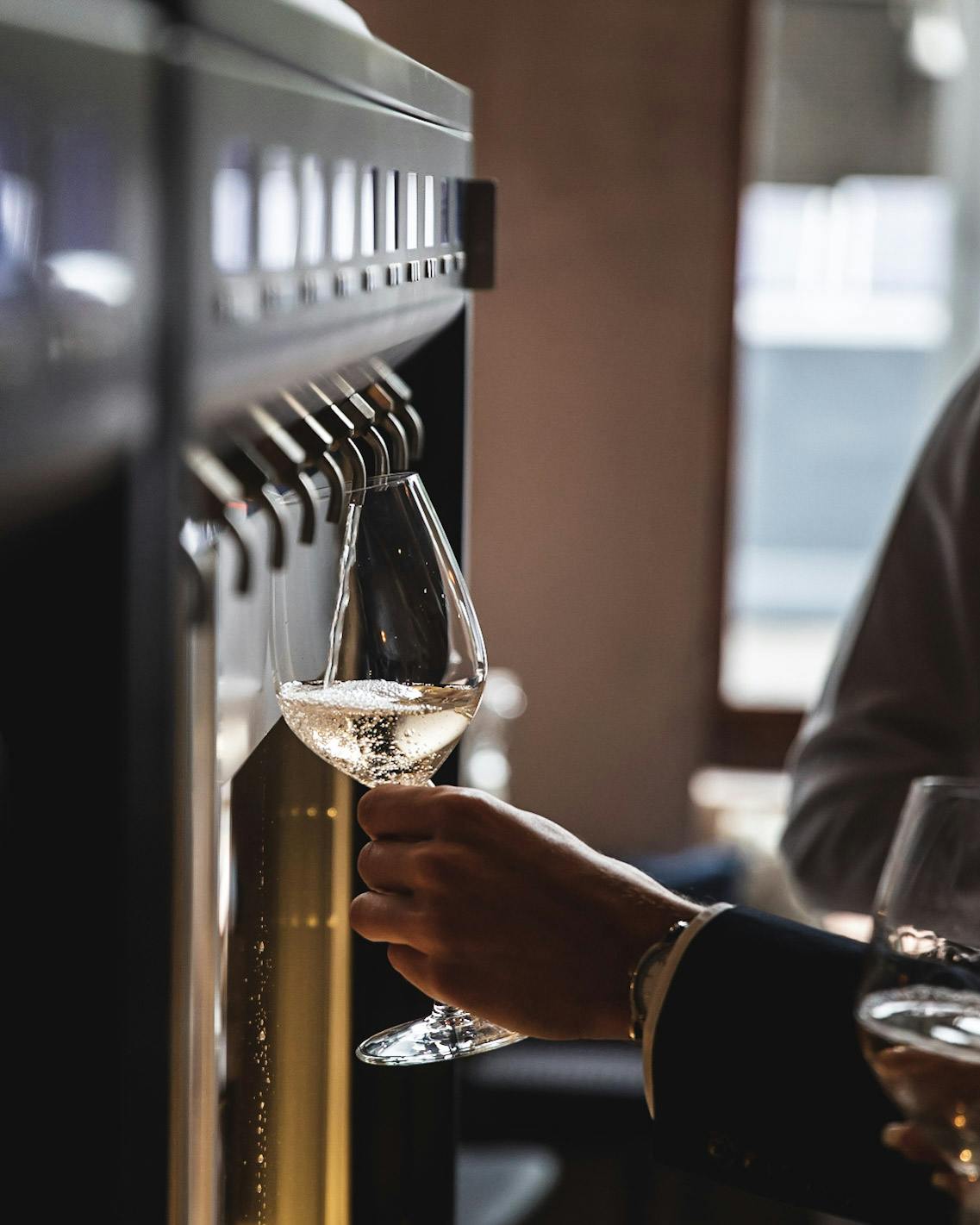 Sleek wine dispenser filling glass with sparkling wine at upscale event in Central Otago.