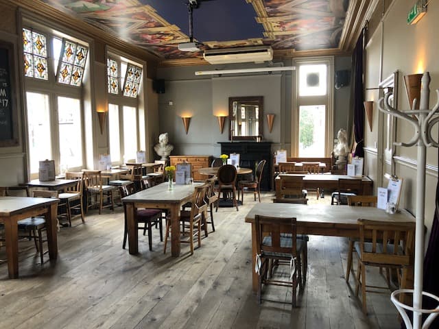 Versatile event space at The Angelic with wooden tables for gatherings or meetings.