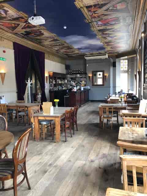 Spacious function room in The Angelic with rustic tables, ideal for events and workshops.