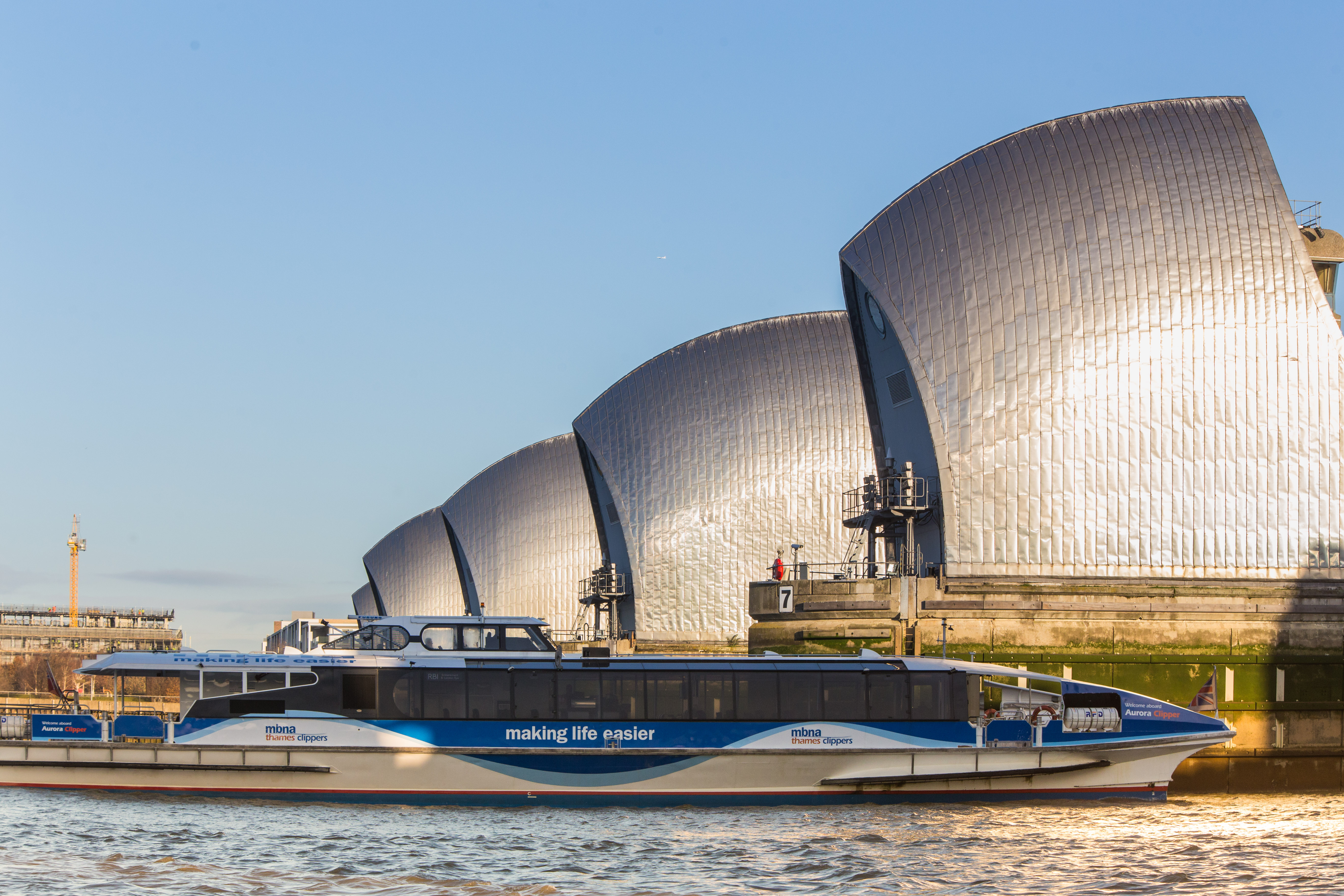 Sleek event boat Venus Clipper near flood barriers for corporate gatherings and private events. - Banner