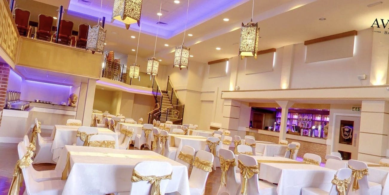 Elegant banqueting suite with white tables and gold accents for weddings or corporate events.