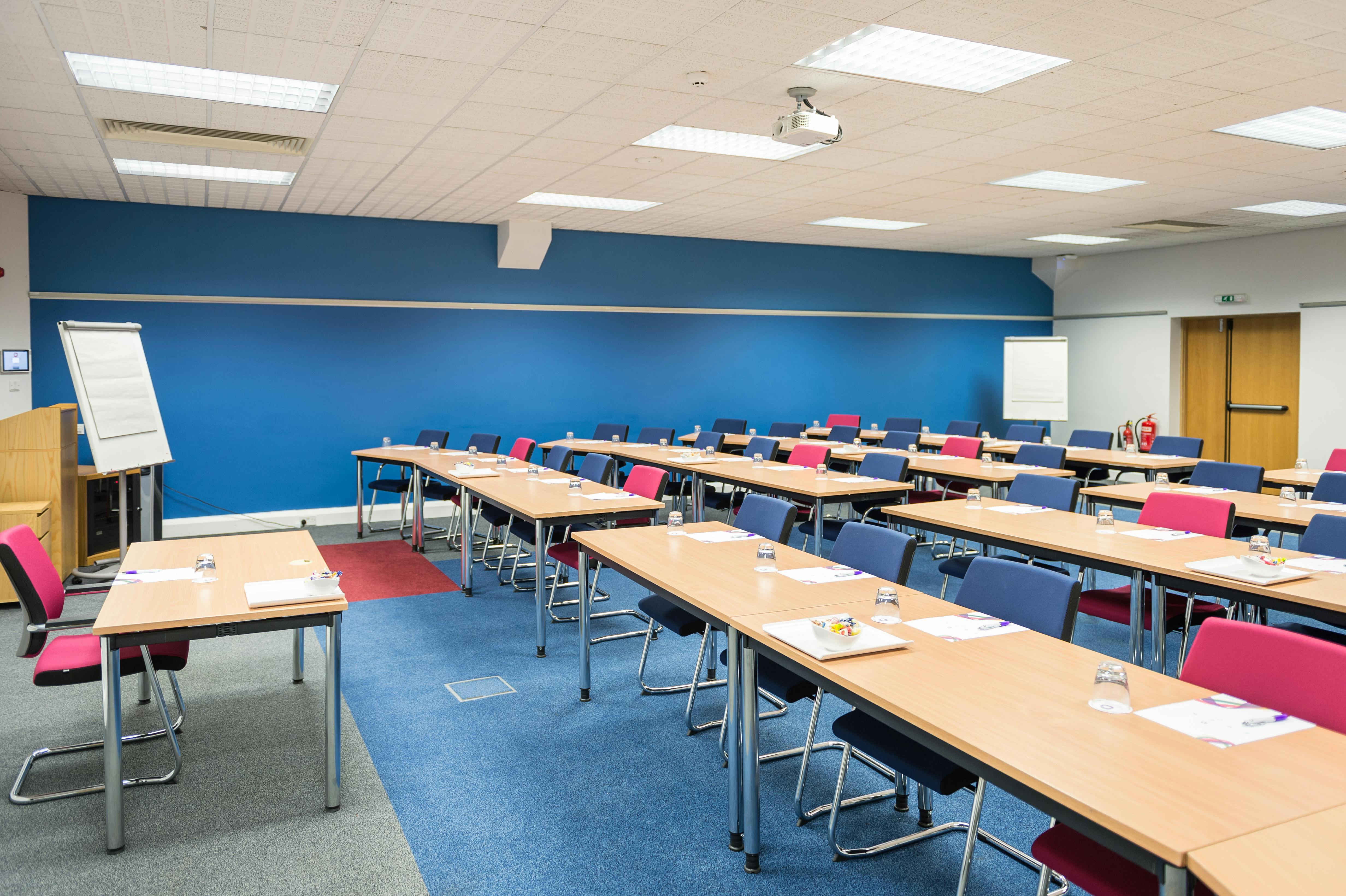 Large meeting room with blue accent wall for workshops at Burleigh Court Conference Centre.