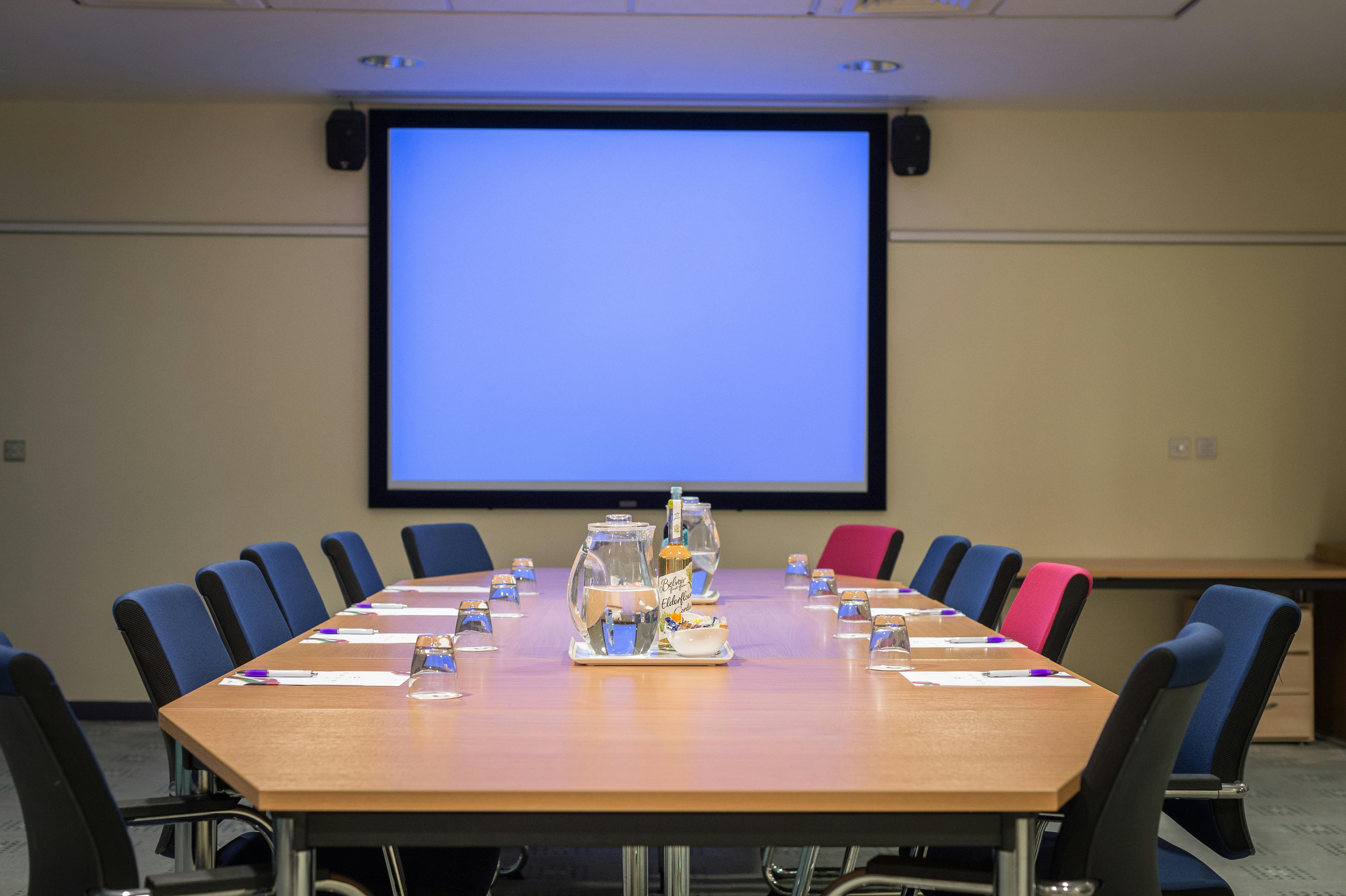 Small meeting room with wooden table, ideal for conferences and training sessions.