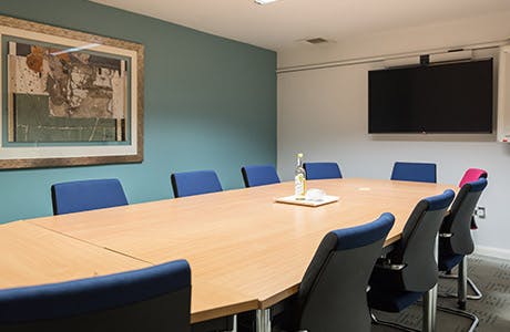 Syndicate Rooms at Burleigh Court: modern meeting space with wooden table and blue chairs.