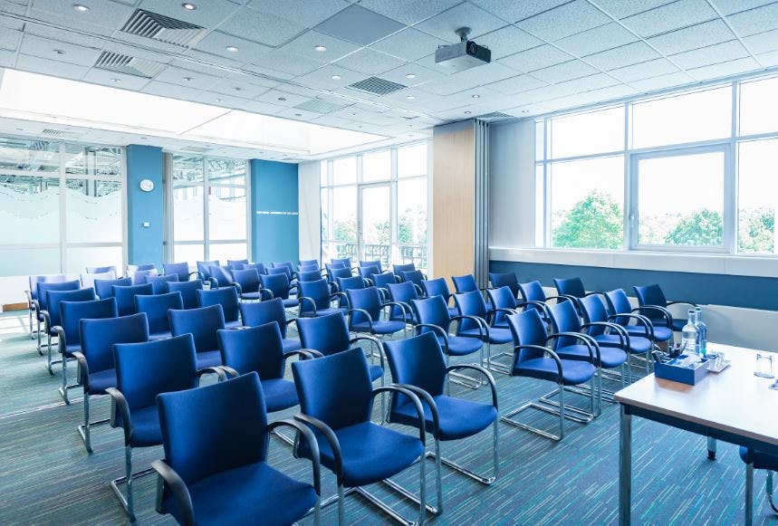 Meeting room with blue chairs, natural light, perfect for conferences and workshops.