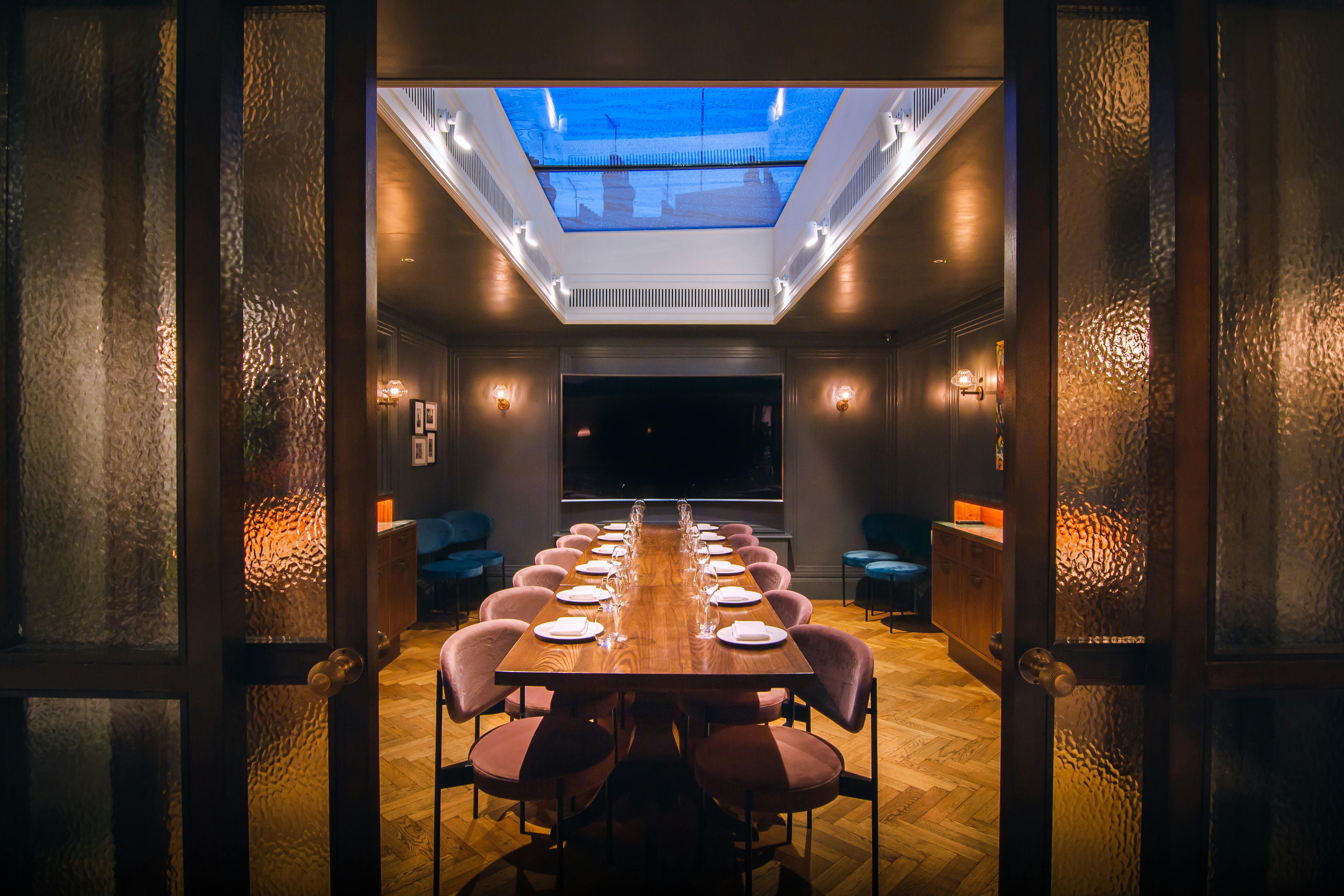 Elegant meeting space with long table and skylight for exclusive events.