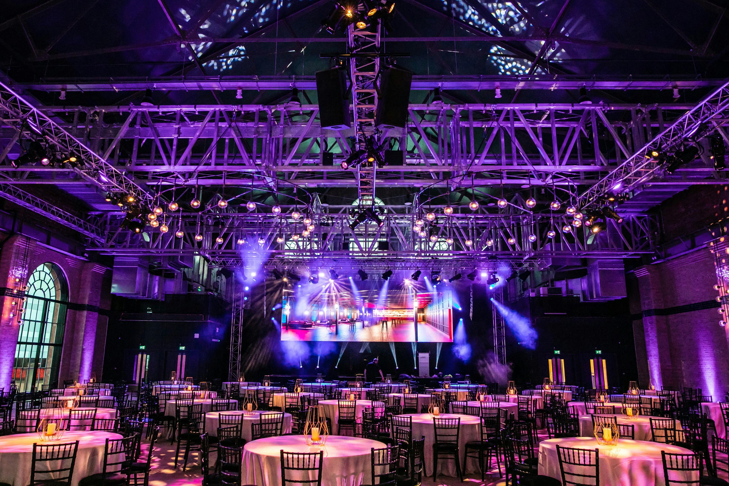 Vibrant event space in Exhibition London with round tables and dramatic lighting for gatherings.