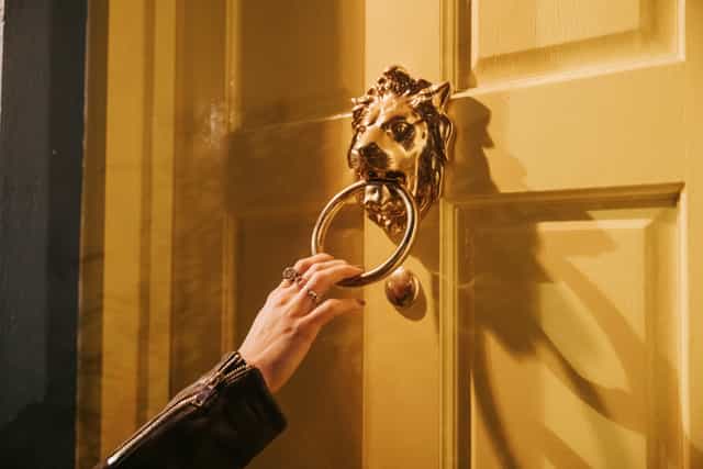 Ornate lion door knocker on vibrant yellow door at The Little Yellow Door venue hire.