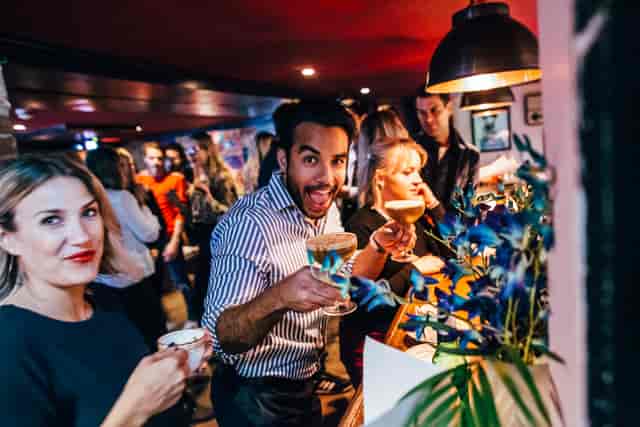 Vibrant social event at Flatmates Den, lively bar with cocktails and networking.