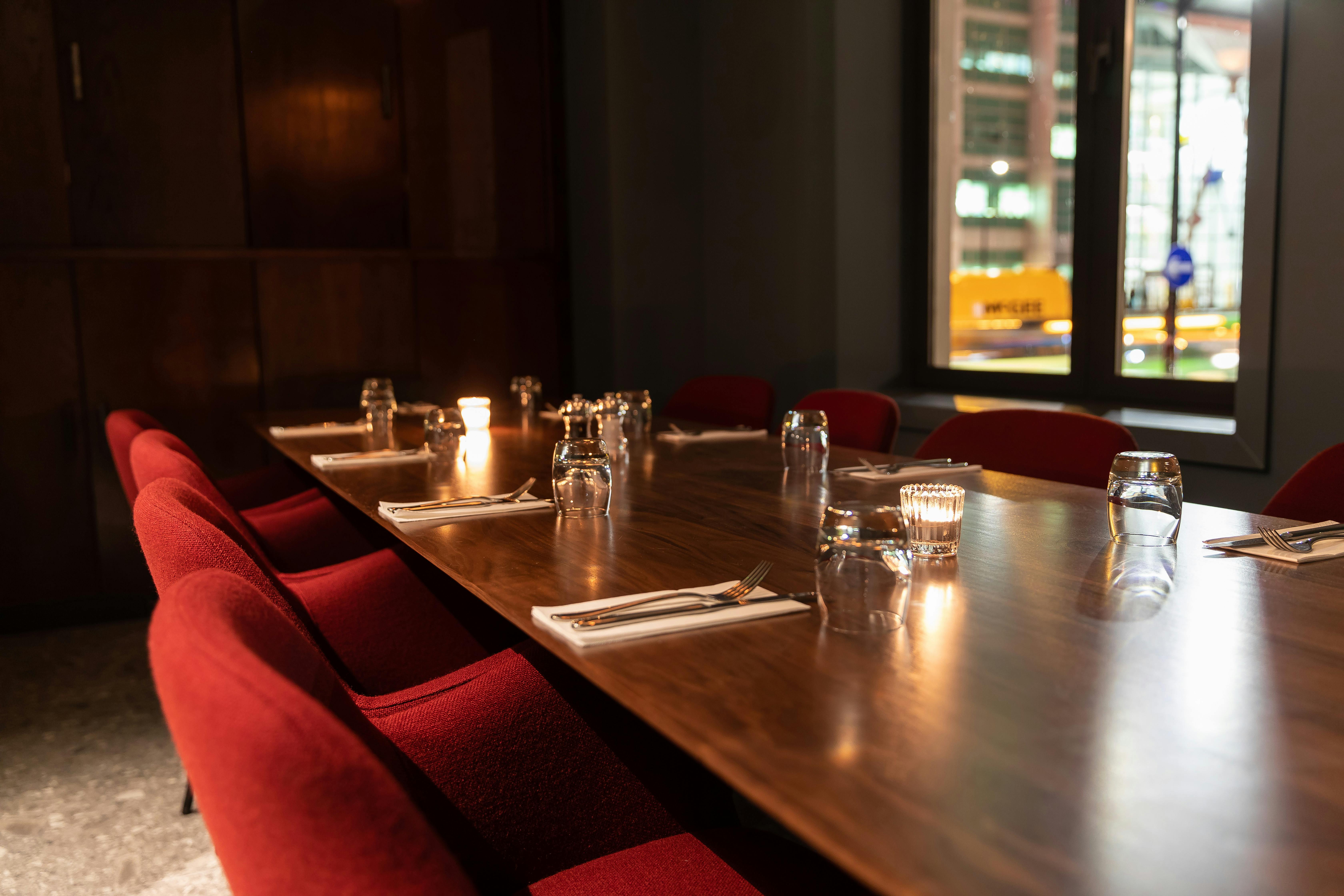 Private dining room with wooden table and red chairs for intimate meetings or events.