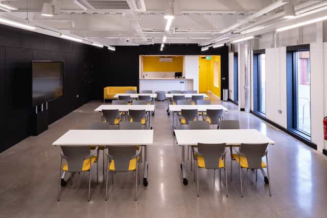 Modern meeting space with yellow accents, perfect for workshops and training sessions.