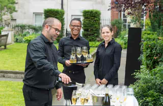 Southwood Garden event with elegant staff serving champagne in lush greenery.