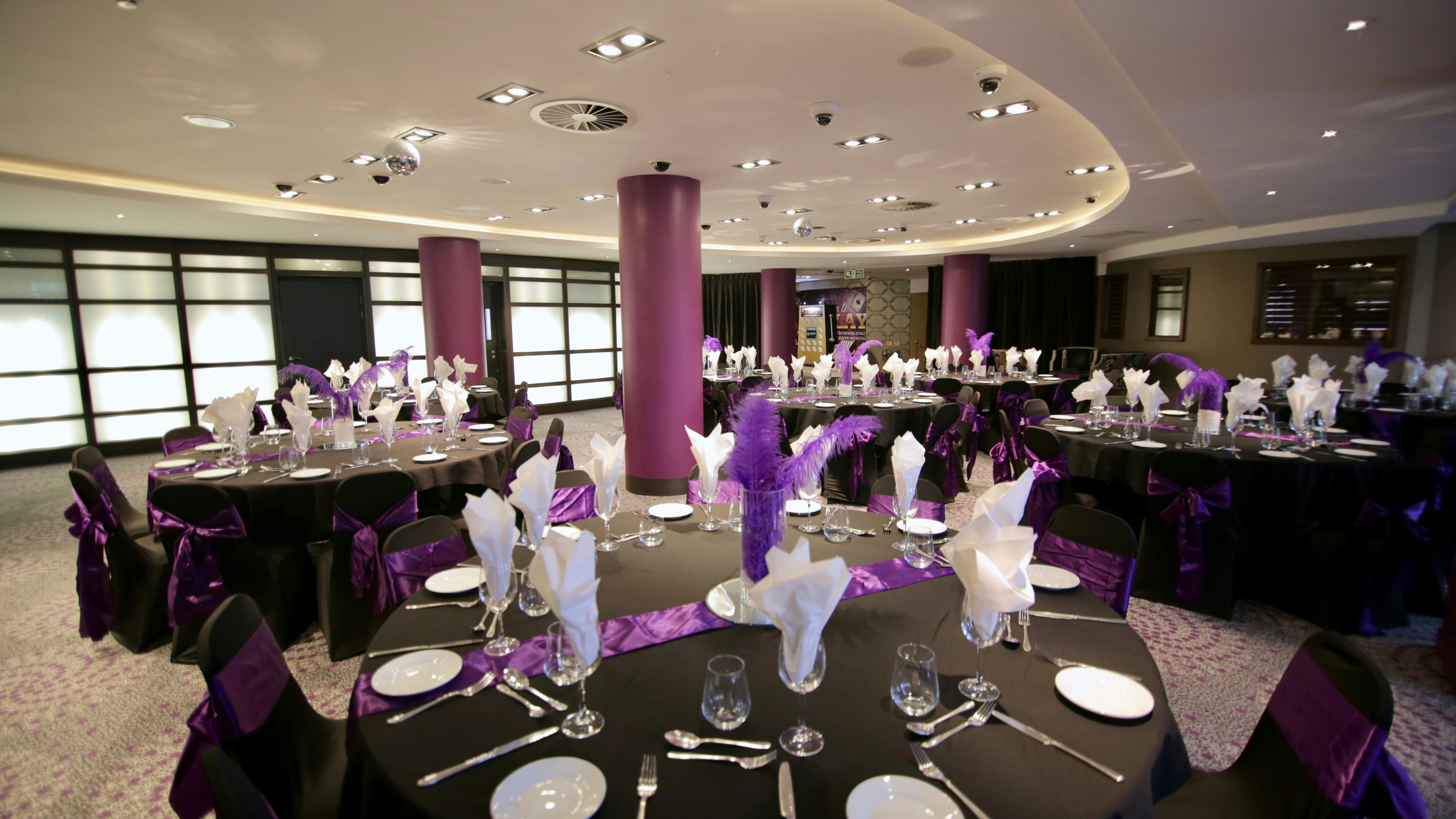 Elegant dinner setup at Alea Casino's Party Pit with black linens and purple accents.