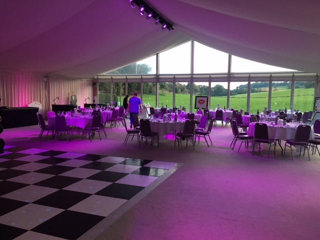 Elegant event space at Broome Park Hotel with round tables and purple lighting.