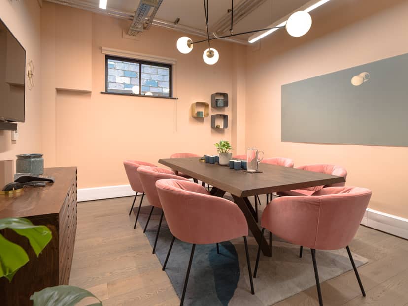 Modern meeting room with pastel pink chairs, ideal for workshops and collaborations.