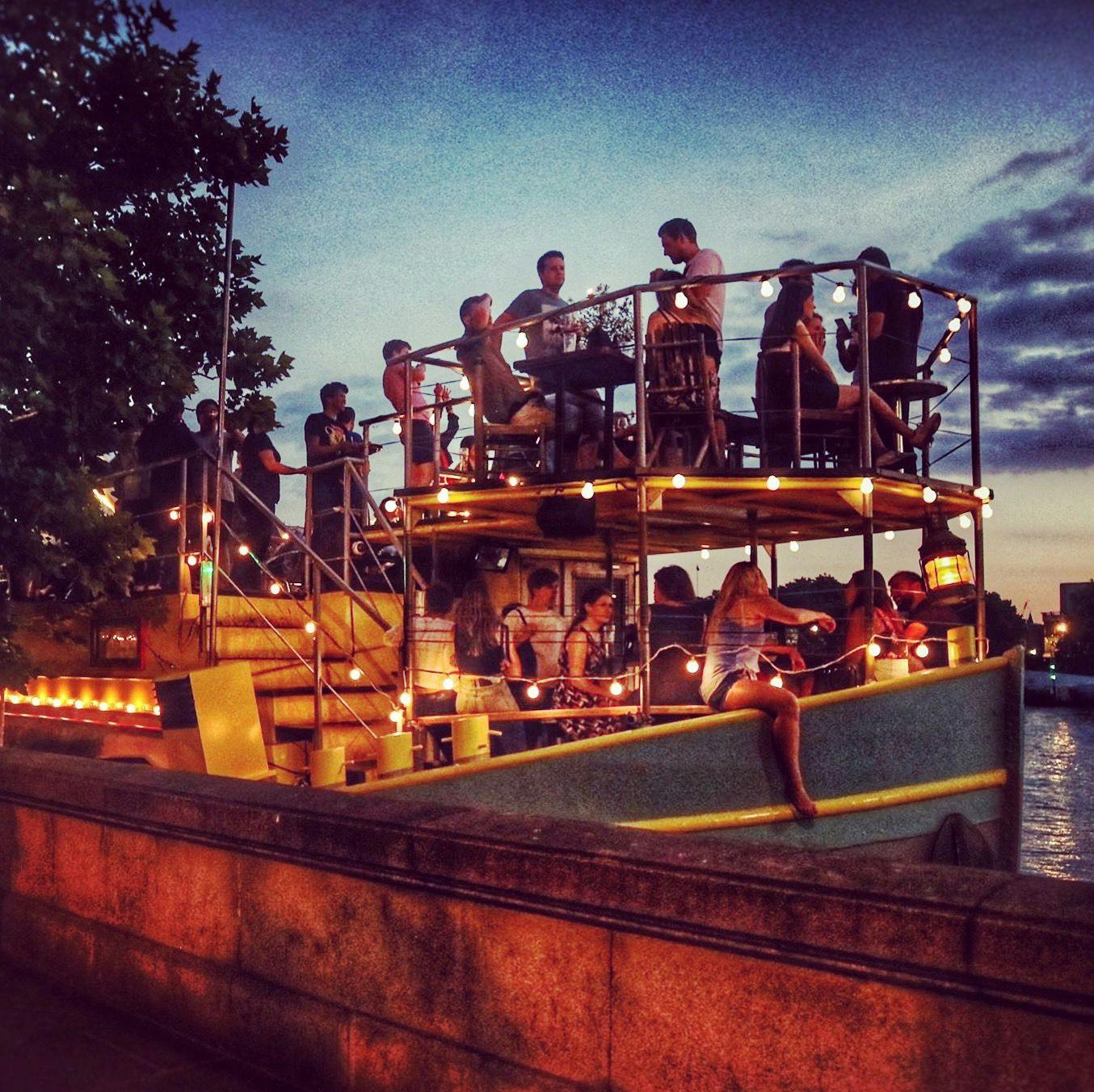 Outdoor event setup at Tamesis Dock with string lights, perfect for networking gatherings.