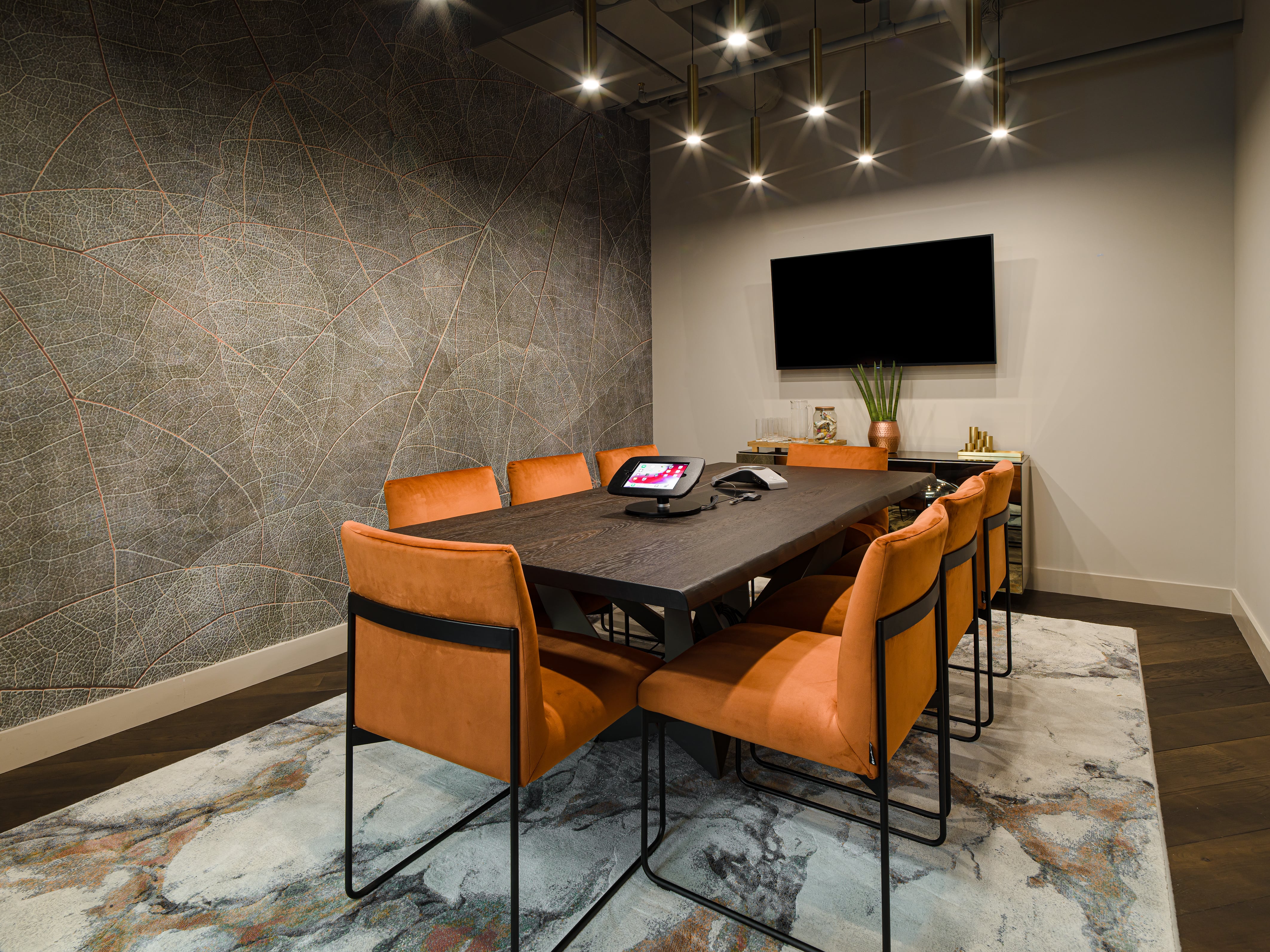 Modern meeting room with sleek table and orange chairs for collaboration events.