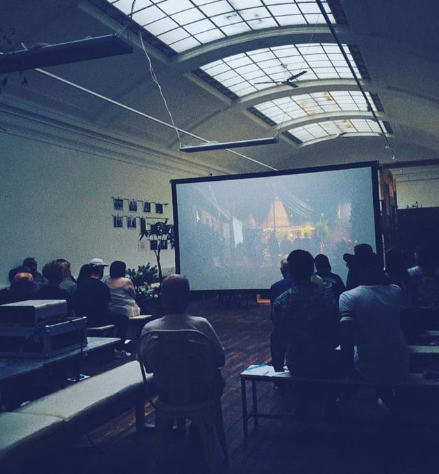 Attendees at a presentation in Medicine Gallery, showcasing a large screen for multimedia events.